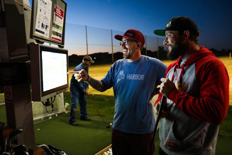 people at night event playing on driving range